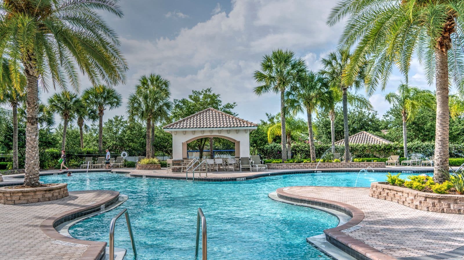A sunny Florida backyard pool framed by palm trees on a bright day